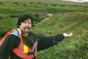 Ted with a grizzle bear in the background over his hand and to the left. 
