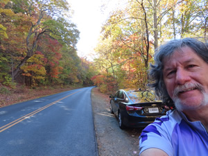 Ted with his rental with the fall colored tress on the road descending from Mount Mitchell.