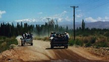People riding in the back of trucks near Calingasta.