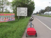Ted’s bike in front of a road sign in Thailand