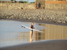 Lady getting ready to surf at beach near El Zunzai, El Salvador