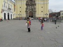 A lady carrying her child in front of San Francisco church in historic center of Lima, Peru.  This church contains thousands of skulls and bones in the basement full of bones, dating from the 1600 to 1808.