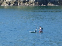 Man fishing from his paddle board in bay of Santa Cruz, Huatulco, Mexico.