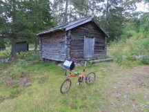 Ted’s bike in front of historic log building near Lövhällan trail on outskirts of Härnösand, Sweden. (Länsmuseets Sjöbodar)