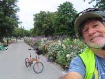 Ted with bike on the sidewalk lined with flowers across from the Biological Museum on Djurgården Island in Stockholm, Sweden.