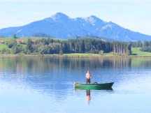 Man fishing from his boat on Hopfensee Lake near Fssen, Germany.