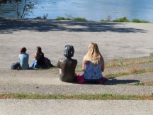Lady sitting with bronze friend at the end of the river trail in Bamberg, Germany.